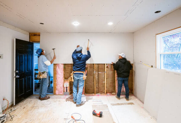 hree men, remodeling contractors, collaborating on a home renovation project with tools and materials around them.